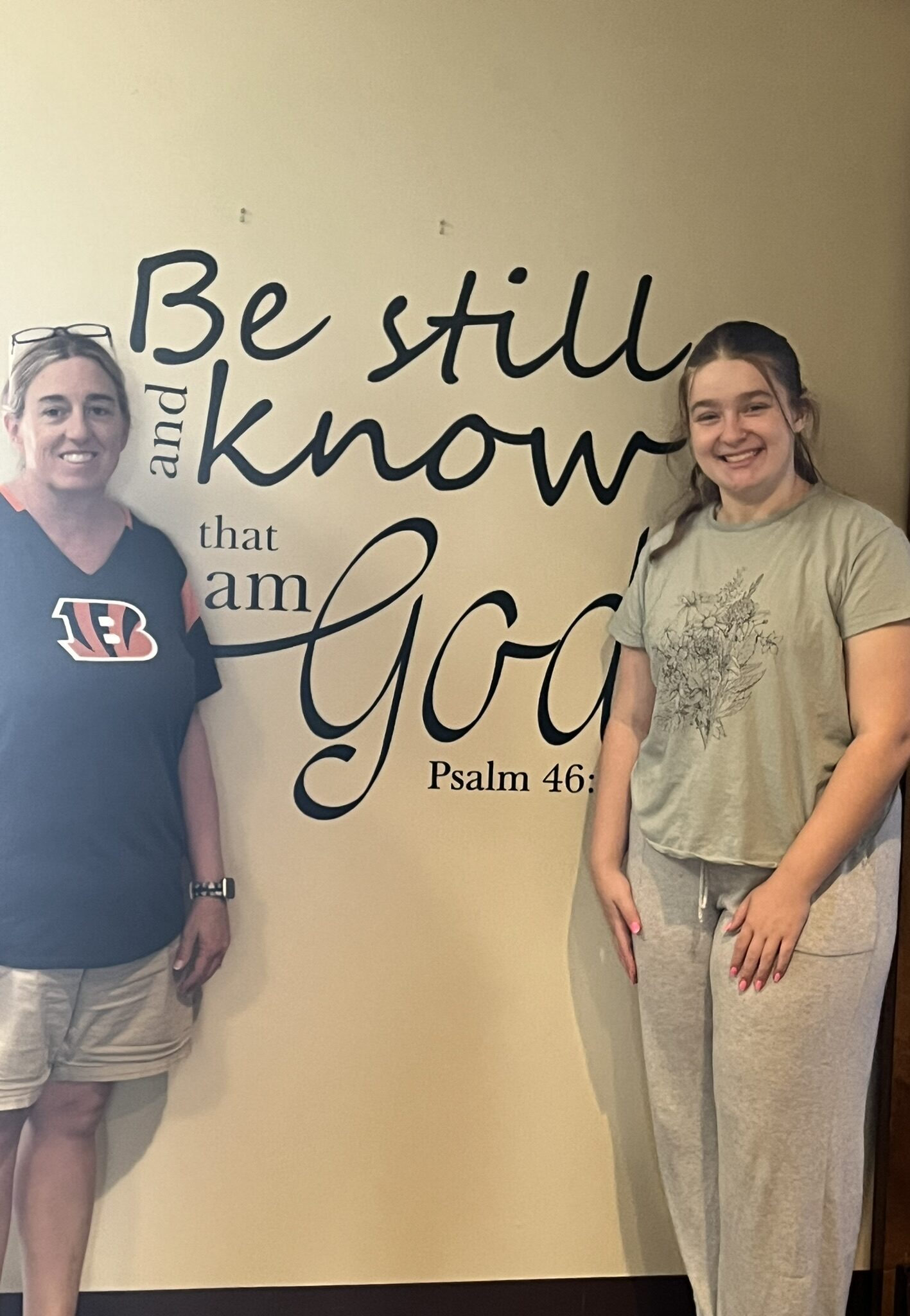 Two members in front of a message saying "Be still and know that I am God".